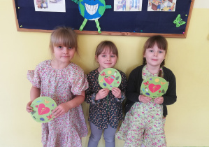 Trzy dziewczynki trzymają medaliony „Przyjaciela natury”